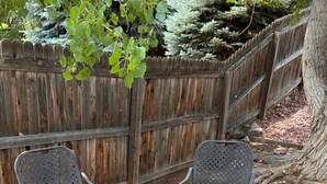 A square outdoor seating area with two chairs and a table, surrounded by a wooden fence and a tree. - 4 Bedroom Mountain Retreat - Garden of the Gods (Colorado Springs)