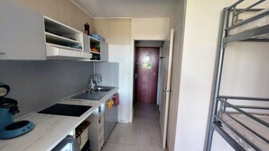 A compact kitchen with a sink, a stove, and cabinets. There is a door leading to another room. - Sea view, beach and port 2m away on foot, private parking  (Agde)