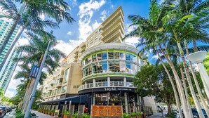 A hotel with a curved facade, outdoor seating area, and palm trees. - Midtown Miami 1BR · Free Parking + Wynwood Nearby (Miami)
