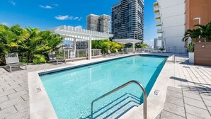 A rooftop swimming pool with lounge chairs, a pergola, and high-rise buildings in the background. - Midtown Miami 1BR · Free Parking + Wynwood Nearby (Miami)