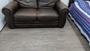 Un canapé en cuir marron dans une pièce dotée d’un plancher en bois et d’une couvre-lit à rayures.