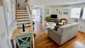 Una sala de estar con sofá, televisor y una escalera que lleva a otra habitación.