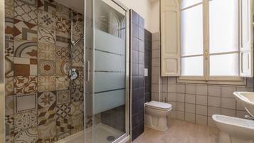 A bathroom with a shower, toilet, and bidet.
