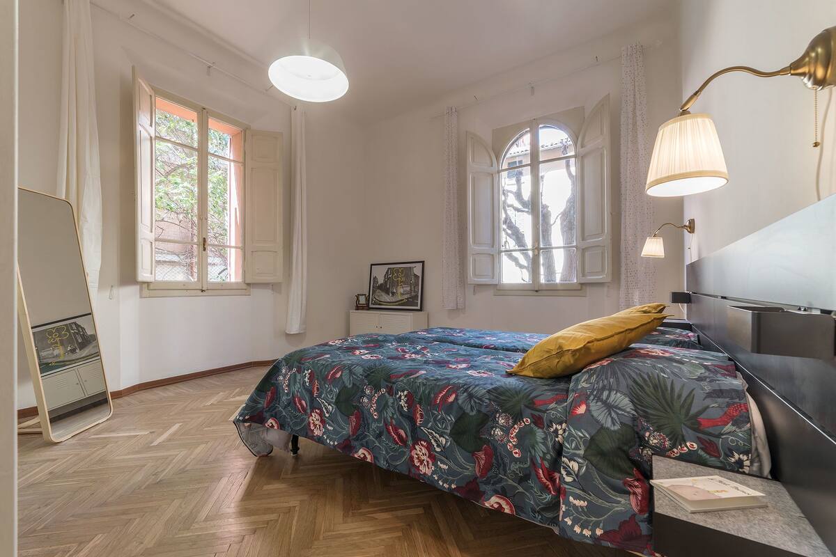 A bedroom with a bed, a mirror, and a window.