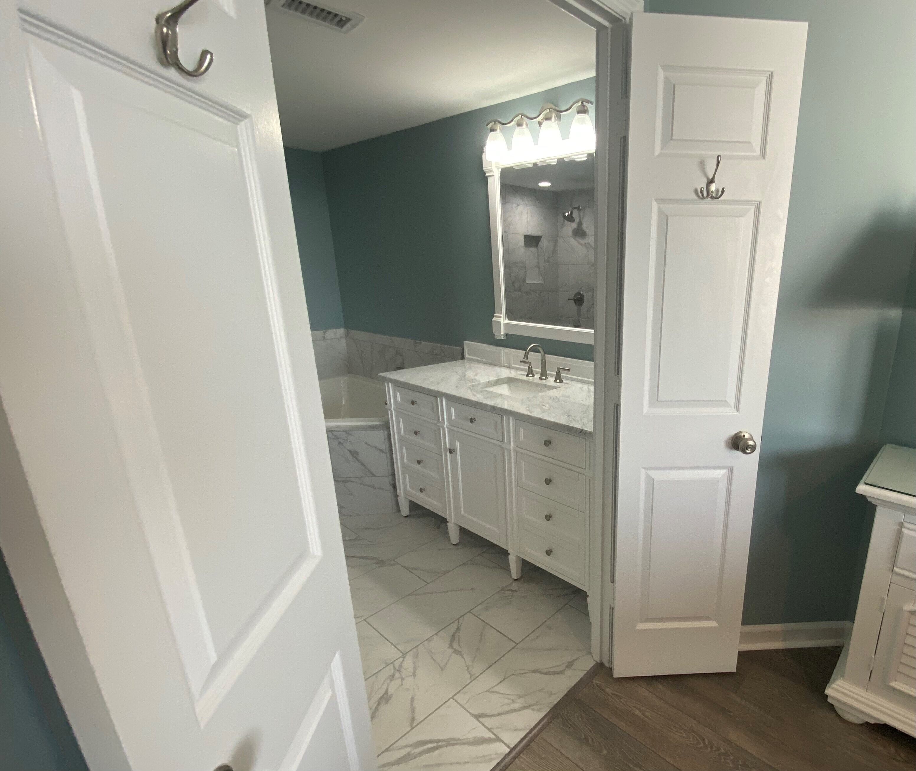 A bathroom with a double sink vanity, a bathtub, and a mirror with lights.