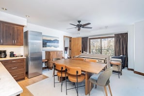 A modern kitchen with a large island, wooden cabinets, and a stainless steel refrigerator.