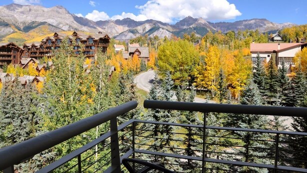 A mountain resort with multiple lodge buildings, surrounded by autumn-colored trees and a view of distant mountains. - Peaks Penthouse #643 (Mountain Village)