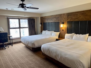 Een hotelkamer met twee bedden, een bureau en een plafondventilator.