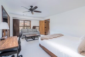 Une chambre d’hôtel avec un lit, un canapé, un bureau et un ventilateur de plafond.