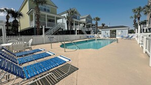 A pool area with lounge chairs and a no lifeguard sign.