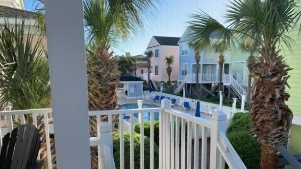 A balcony with a wooden floor, white railing, and a chair.