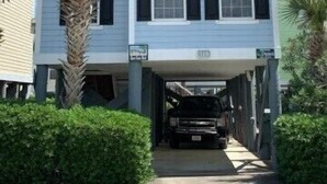 A two-story building with a garage entrance, surrounded by greenery.