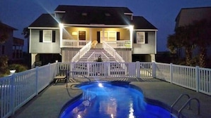 Uma casa de dois andares com varanda frontal e piscina.