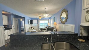 A kitchen with a black granite countertop, stainless steel sink, and a ceiling fan. - Dolphin Cove 3A - Oceanfront Condominium in Garden City Beach (Garden City)