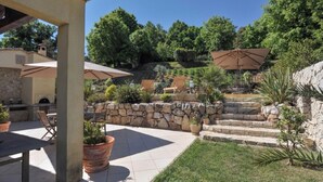 Un espace extérieur aménagé en terrasse, avec des marches en pierre, des plantes en pot et du mobilier de jardin.