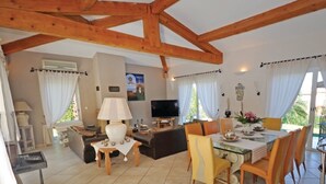 Un grand espace de vie comprenant une table à manger, des chaises, un canapé et un téléviseur.