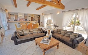 A living room with a sofa set, a coffee table, and a dining area in the background. - Magnificent quiet villa with swimming pool 7 min from Mandelieu (Les adrets de l'esterel)