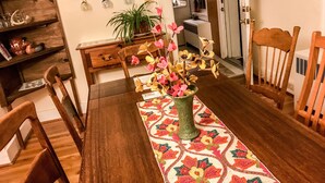 A dining area with a wooden table, chairs, a patterned table runner, and a vase with flowers. - Coburn On the Creek - Flyfish, Tube , Grill, Relax- PSU Football/Camp Woodward (Coburn)