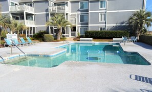 A swimming pool with clear water, surrounded by lounge chairs and palm trees. - Sea Cloisters I 101B - Oceanfront Condominium in Surfside Beach (Surfside Beach)