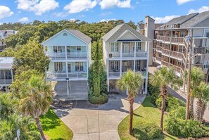 A beachfront property with multiple-story buildings, a covered walkway, and palm trees.