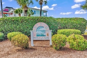A sign for Seaford Village with a clear view of the surrounding greenery and a house in the background.