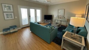 A living room with a teal sofa, a coffee table, a TV, and a ceiling fan.