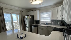 Een moderne keuken met witte kasten, een roestvrijstalen koelkast, een inbouwoven en een groot kookeiland met spoelbak.