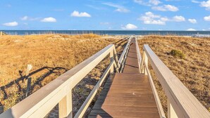 Un muelle de madera que conduce a una playa bajo un cielo despejado.