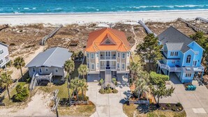 Una propiedad frente a la playa con tres casas, una terraza de madera y una vista despejada del océano.