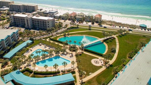 A resort with multiple swimming pools, a bridge, and a beach.