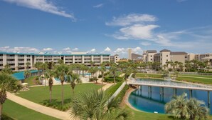 A hotel with multiple balconies, a swimming pool, and palm trees.