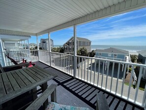 Enjoy the ocean view from this balcony with a table and chairs.
