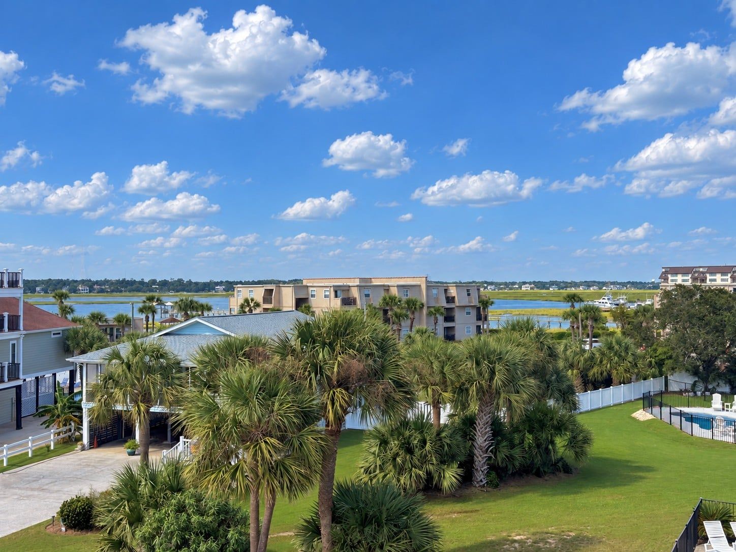 A residential area with a view of a body of water, a swimming pool, and a large building with multiple floors.
