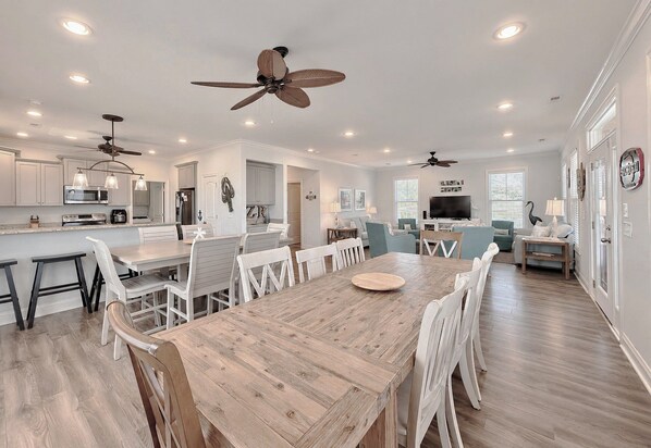A spacious kitchen with modern appliances, a dining area with a wooden table, and a living room with a television. - Buckeye Heaven - Second Row in Garden City Beach (Garden City Beach)