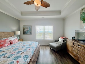 A bedroom with a bed, a chair, a dresser, a painting, and a window with blinds. - Buckeye Heaven - Second Row in Garden City Beach (Garden City Beach)