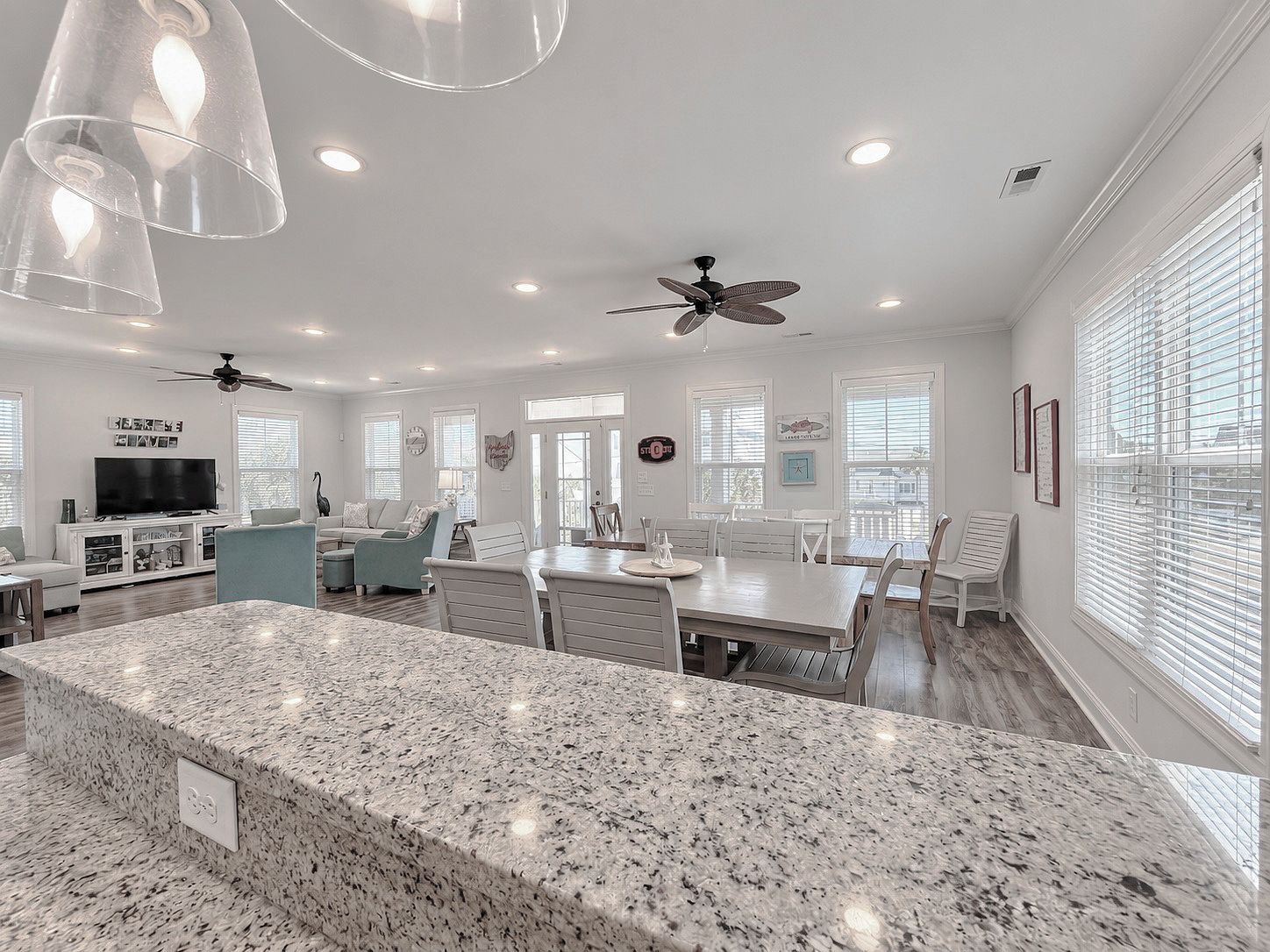 A spacious living area with a granite island, ceiling fans, and a dining table.