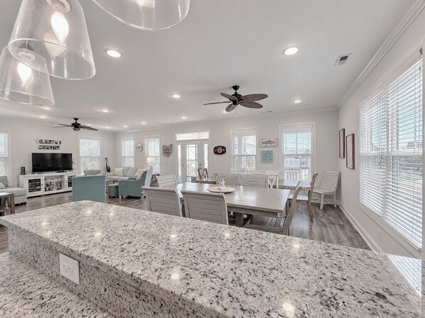 A spacious living area with a granite island, ceiling fans, and a dining table. - Buckeye Heaven - Second Row in Garden City Beach (Garden City Beach)