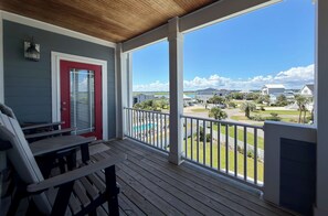 A covered porch with a view of a residential area, including houses and a body of water. - Buckeye Heaven - Second Row in Garden City Beach (Garden City Beach)