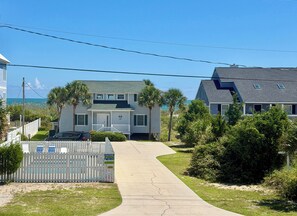 A residential street with houses, a sidewalk, and a white picket fence.