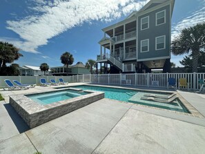 A pool area with a rectangular pool, lounge chairs, and a multi-story building with balconies.