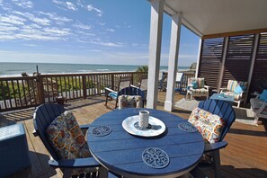 Une terrasse avec une table et des chaises, donnant sur l’océan.