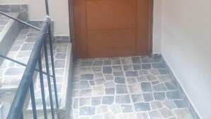 Uma porta de madeira com o número 202, um corrimão de metal e piso de azulejos.