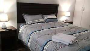 A neatly made bed with striped bedding, two bedside tables with lamps, and a wardrobe in a hotel room. - LIMA FLAT 1 1D (10 MIN FROM MIRAFLORES) (Lima)