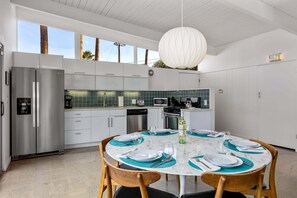 A modern kitchen with a marble island, stainless steel appliances, and teal accents. - Desert Eden – Midcentury Pool Oasis (Palm Springs)