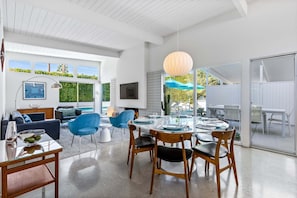 A modern interior with a dining area, a sofa, and a TV.