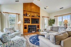 A spacious living room with a fireplace, two sofas, a coffee table, and a television. - The Taylor at Ships Watch in Duck (Duck)