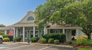 A two-story building with a covered porch, a flag, and a parking lot. - The Taylor at Ships Watch in Duck (Duck)