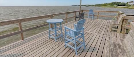 Una terraza de madera con una mesa y sillas, con vista a un cuerpo de agua.
