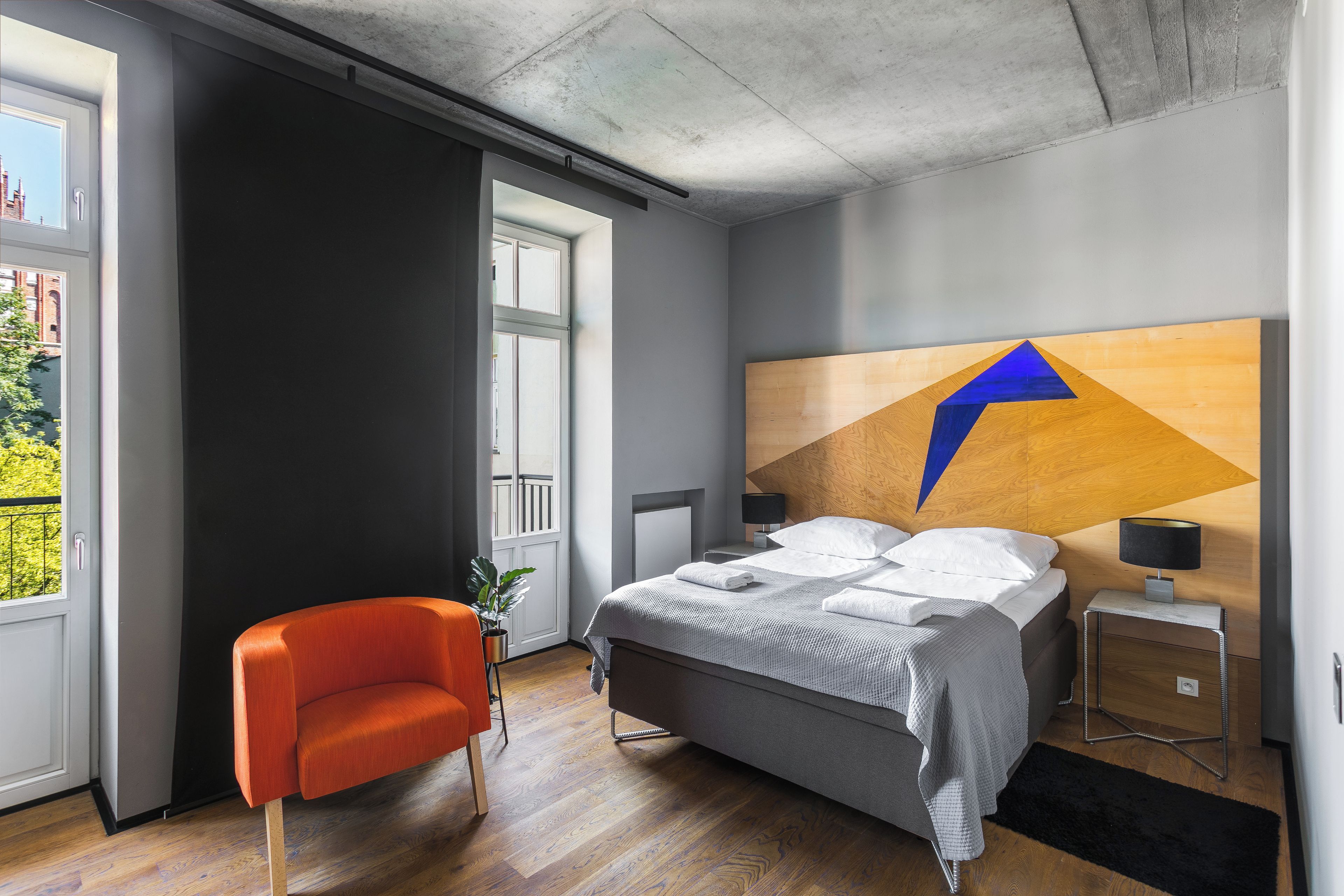 Une chambre à coucher moderne, avec un lit, une chaise, une table de chevet et une vue sur l’extérieur.