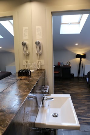 A modern bathroom with a large mirror, a sink, and two hair dryers mounted on the wall. - Dada Premium Aparthotel (Kraków)